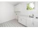 Clean laundry room with patterned tile floor, white cabinets, sink, and countertop at 1301 Doylin Dr, Cary, NC 27511