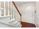 Traditional staircase with white spindles and a dark wood banister next to a white door at 1324 Swallow Dr, Raleigh, NC 27606