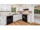 Bright kitchen with white cabinets, black appliances, light countertops, wood floors and natural light from the window at 1604 Westbridge Ct, Raleigh, NC 27606