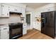 Bright kitchen with white cabinets, black appliances, light countertops, wood floors and opens to another room at 1604 Westbridge Ct, Raleigh, NC 27606