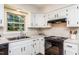Bright kitchen with white cabinets, black appliances, light countertops, wood floors and natural light from the window at 1604 Westbridge Ct, Raleigh, NC 27606