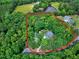 Aerial view of a wooded property with a lovely house surrounded by trees and a pond in the background at 168 E Deer, Apex, NC 27523