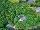 Aerial view of a wooded property with a lovely house surrounded by trees and a pond in the background at 168 E Deer, Apex, NC 27523