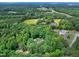 An aerial view of the expansive wooded property with a pond and rolling hills in the distance at 168 E Deer, Apex, NC 27523