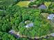 Aerial view of a wooded property with a lovely house surrounded by trees and a pond in the background at 168 E Deer, Apex, NC 27523