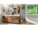 Bathroom featuring double sinks, oak cabinets, a tub, and a window with natural light at 168 E Deer, Apex, NC 27523