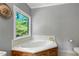 Bathroom soaking tub with a wooden base is lit by a window overlooking a lush green landscape at 168 E Deer, Apex, NC 27523