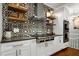 Custom kitchen with patterned backsplash, stainless range hood, pot filler, and floating wood shelves at 168 E Deer, Apex, NC 27523