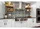 Close up of designer kitchen with patterned backsplash, floating wood shelves, and stainless steel range at 168 E Deer, Apex, NC 27523