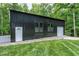 Large outbuilding featuring a garage door, pedestrian door, and windows surrounded by gravel and grass at 168 E Deer, Apex, NC 27523