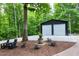 Spacious outbuilding with two garage doors and gravel driveway is set amongst lush trees at 168 E Deer, Apex, NC 27523