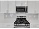Close up of the kitchen with stainless steel microwave, gas range, and gray tiled backsplash at 172 Wellons Creek Dr, Garner, NC 27529