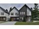 Modern two-story home boasts a combination of gray brick and white siding and a well manicured lawn at 1802 Pershing Rd, Raleigh, NC 27608