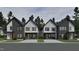 Street view of modern homes featuring a mix of gray brick and white siding and a well manicured lawn at 1802 Pershing Rd, Raleigh, NC 27608