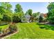 Large backyard with a lush lawn, landscaping, and mature trees surrounding the property at 2111 Woodland Ave, Raleigh, NC 27608
