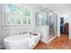 Spa-like bathroom featuring a soaking tub, a shower, and plantation shutters at 2111 Woodland Ave, Raleigh, NC 27608