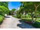 Charming home exterior with a gravel driveway, mature trees, and lush landscaping at 2111 Woodland Ave, Raleigh, NC 27608