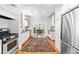 Open kitchen with white cabinets, stainless steel appliances, hardwood floors, and seamless transition to dining area at 2111 Woodland Ave, Raleigh, NC 27608