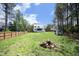 Large backyard with a fence, green grass, a shed, and a wood pile in the center at 2200 Mays Crossroads Rd, Louisburg, NC 27549