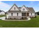 Inviting home featuring a stone foundation, manicured lawn, beautiful landscaping, and a charming front porch at 25 Deer Tail Ln # 52, Fuquay Varina, NC 27526