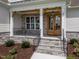 Charming front porch with stone accents, a wooden door, and decorative landscaping for a welcoming entrance at 25 Deer Tail Ln # 52, Fuquay Varina, NC 27526