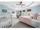 Bright bedroom with a ceiling fan, tray ceiling, light blue walls, and a crib in the foreground at 2506 Blooming St, Raleigh, NC 27612