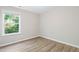 A cozy bedroom with a bright window overlooking lush greenery, complemented by modern flooring at 2513 Magnolia Tree Ln, Durham, NC 27703