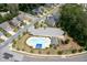 Aerial view of the community pool with a playground, parking, and lounging area surrounded by mature trees at 2513 Magnolia Tree Ln, Durham, NC 27703