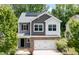 Two-story home with stone accents, a two-car garage, and solar panels surrounded by beautiful green trees at 2513 Magnolia Tree Ln, Durham, NC 27703