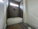 Modern bathroom features a bright white bathtub under a window and dark gray tiling at 269 Deer Tail Ln # 44, Fuquay Varina, NC 27526