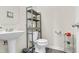 Compact bathroom featuring a pedestal sink, toilet, and functional storage shelves at 4108 Lady Slipper Ln, Durham, NC 27704