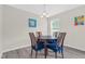 A dining room with a round wood table, blue chairs, and light fixture at 4108 Lady Slipper Ln, Durham, NC 27704