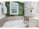 Bright bathroom featuring a soaking tub with a unique plant-themed accent wall at 429 Marsh Landing Dr, Holly Springs, NC 27540