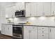 Kitchen with stainless steel appliances, white cabinetry, granite counters and herringbone-patterned backsplash at 4504 Beckel Rd, Willow Springs, NC 27592