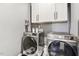 Well-equipped laundry room showcasing modern front-load washer and dryer units and ample white cabinet storage above at 4504 Beckel Rd, Willow Springs, NC 27592