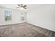 A large empty bedroom featuring neutral carpet, white walls, two windows, and a ceiling fan at 51 Duchess Ave, Franklinton, NC 27525