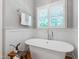 Modern bathroom features a freestanding tub, marble tile wainscoting, and plantation shutters at 6 Castlewood Dr, Durham, NC 27713