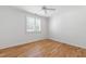 White bedroom features hardwood floors, window, and ceiling fan at 6 Castlewood Dr, Durham, NC 27713