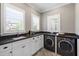 Laundry room with front-load washer and dryer, black countertops, shaker cabinets, and bright windows at 6 Castlewood Dr, Durham, NC 27713