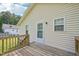 View of the home's yellow siding with a wooden back deck and door at 6904 Fox Haven Pl, Raleigh, NC 27616