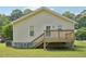 Back of house with yellow siding, a deck with stairs, and a partial foundation view at 6904 Fox Haven Pl, Raleigh, NC 27616