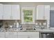 Stylish kitchen offers white cabinets, stainless steel sink, and gray subway tile backsplash at 6904 Fox Haven Pl, Raleigh, NC 27616