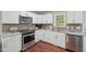 Well-lit kitchen boasts white cabinets, stainless steel appliances, and dark hardwood floors at 6904 Fox Haven Pl, Raleigh, NC 27616