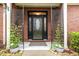 Elegant front entrance with a black door, glass panels, potted plants, and brick siding at 8005 Crookneck Dr, Angier, NC 27501