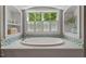 Close-up of a luxurious soaking tub with blue tile accents, a large window with green views, and built-in shelves at 8232 Glynmorgan Way, Chapel Hill, NC 27516