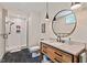 Modern bathroom featuring a wood vanity, marble countertop, a round mirror, and a glass-enclosed shower at 8232 Glynmorgan Way, Chapel Hill, NC 27516