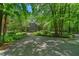 View of a charming two-story home with a stone driveway surrounded by lush, mature trees and landscaping at 8232 Glynmorgan Way, Chapel Hill, NC 27516