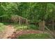 A tranquil garden retreat with a rustic wooden gate, mulch path, and surrounded by a lush green forest at 8232 Glynmorgan Way, Chapel Hill, NC 27516