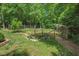 A serene garden area with a charming wooden gate, lush plants, and mulch pathways nestled among mature trees at 8232 Glynmorgan Way, Chapel Hill, NC 27516