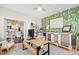 Inviting home office area with stylish decor, leafy wallpaper, desk, and seamless transition to the kitchen at 8613 Swarthmore Dr, Raleigh, NC 27615